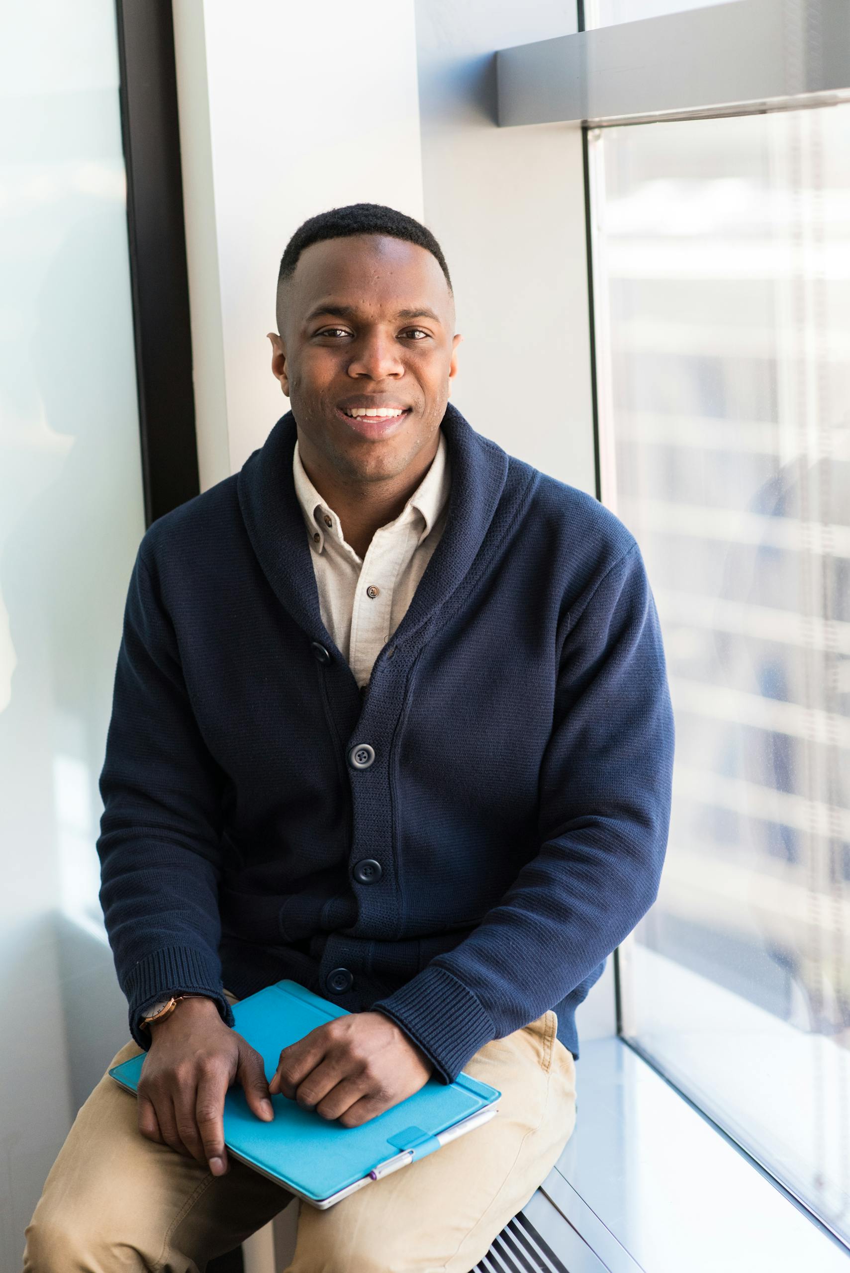 a-professional-black-man-smiling-while-seated-by-a-window-embodying-modern-business-vibes.